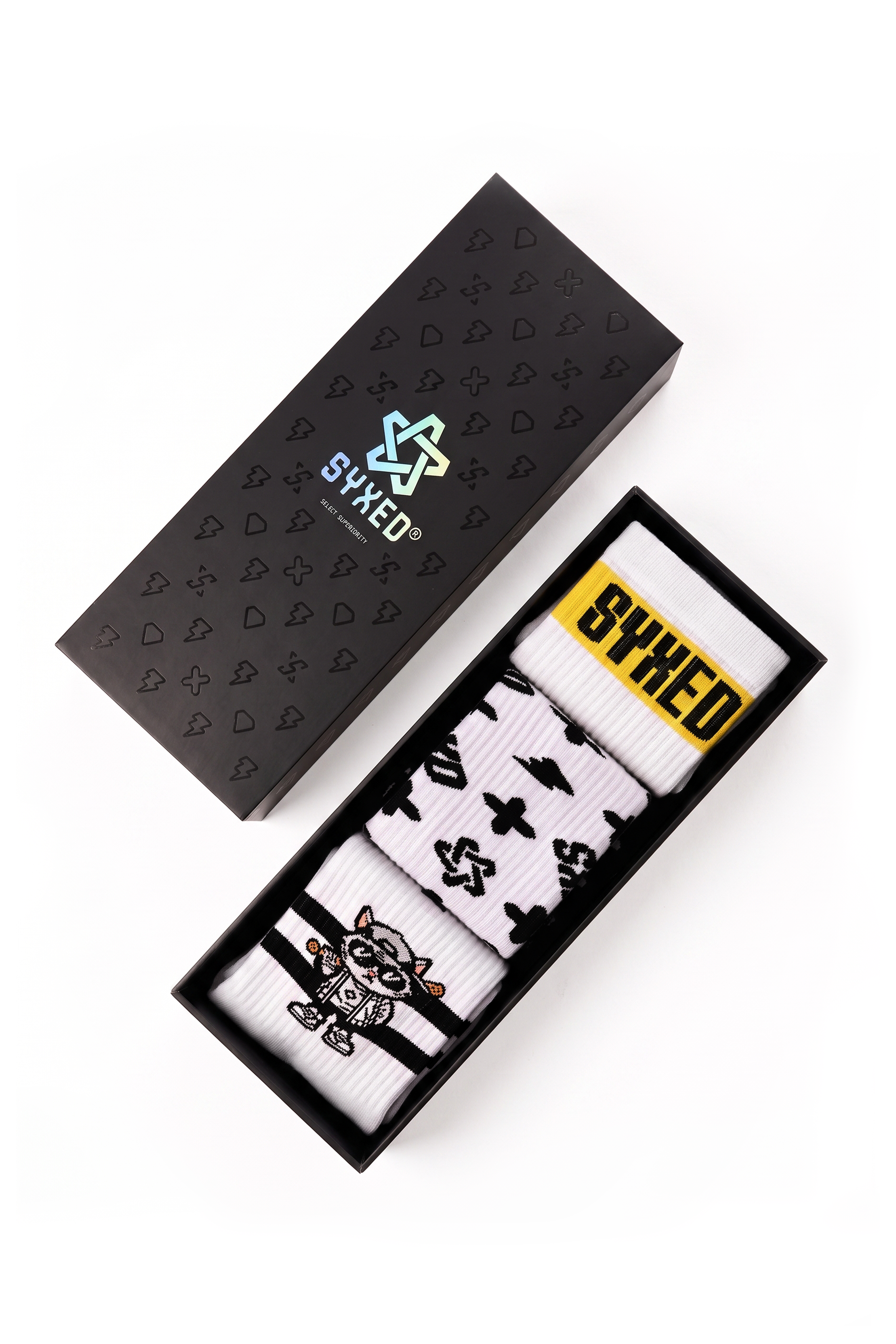 A boxed pair of white socks with black graphics and a yellow SYXED label, shown next to a black presentation box with the SYXED logo on a white background.