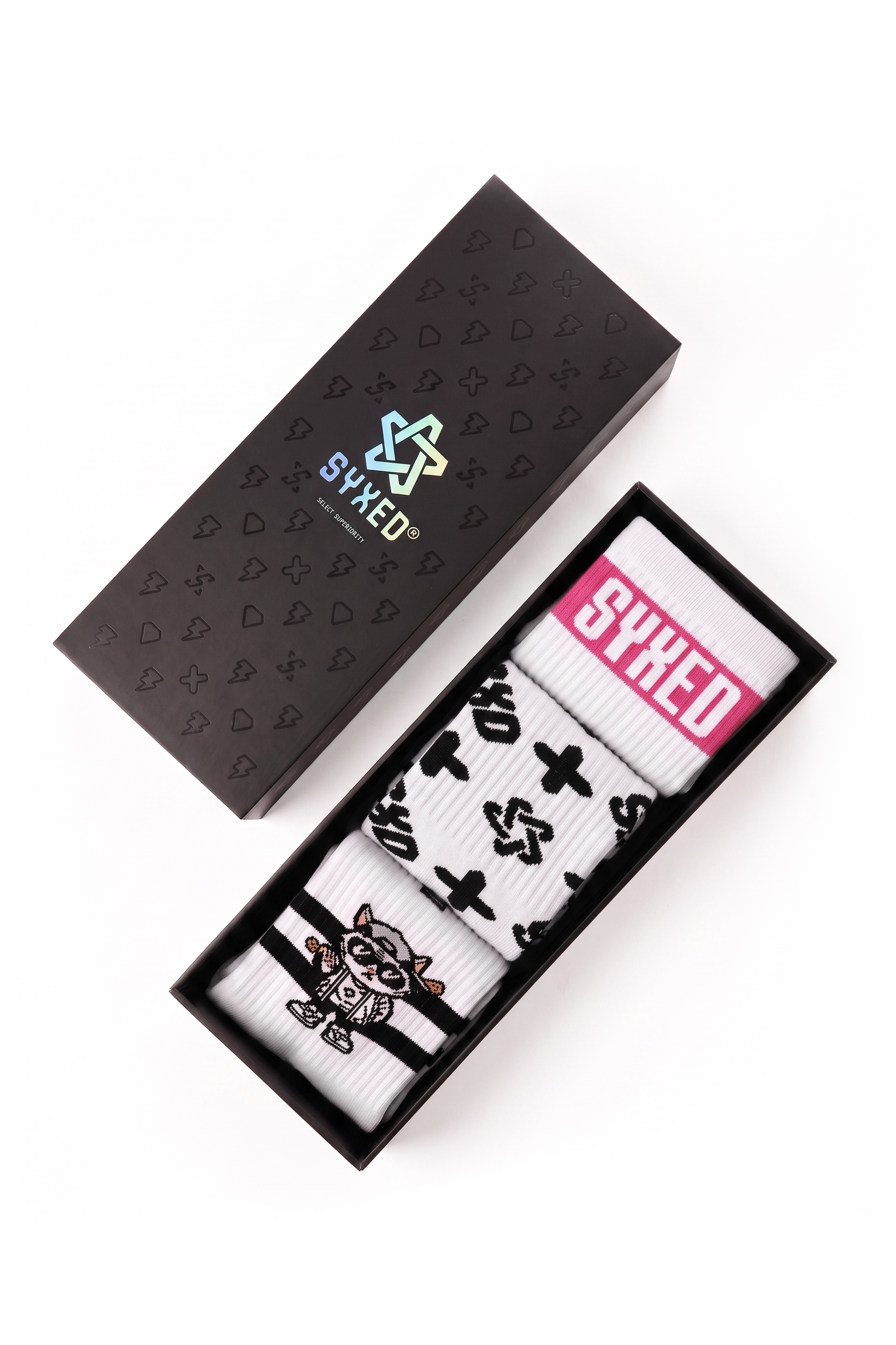 A pair of white socks with black graphic prints and a pink 'SYXED' label, presented in a black box next to its branded black lid on a white background.