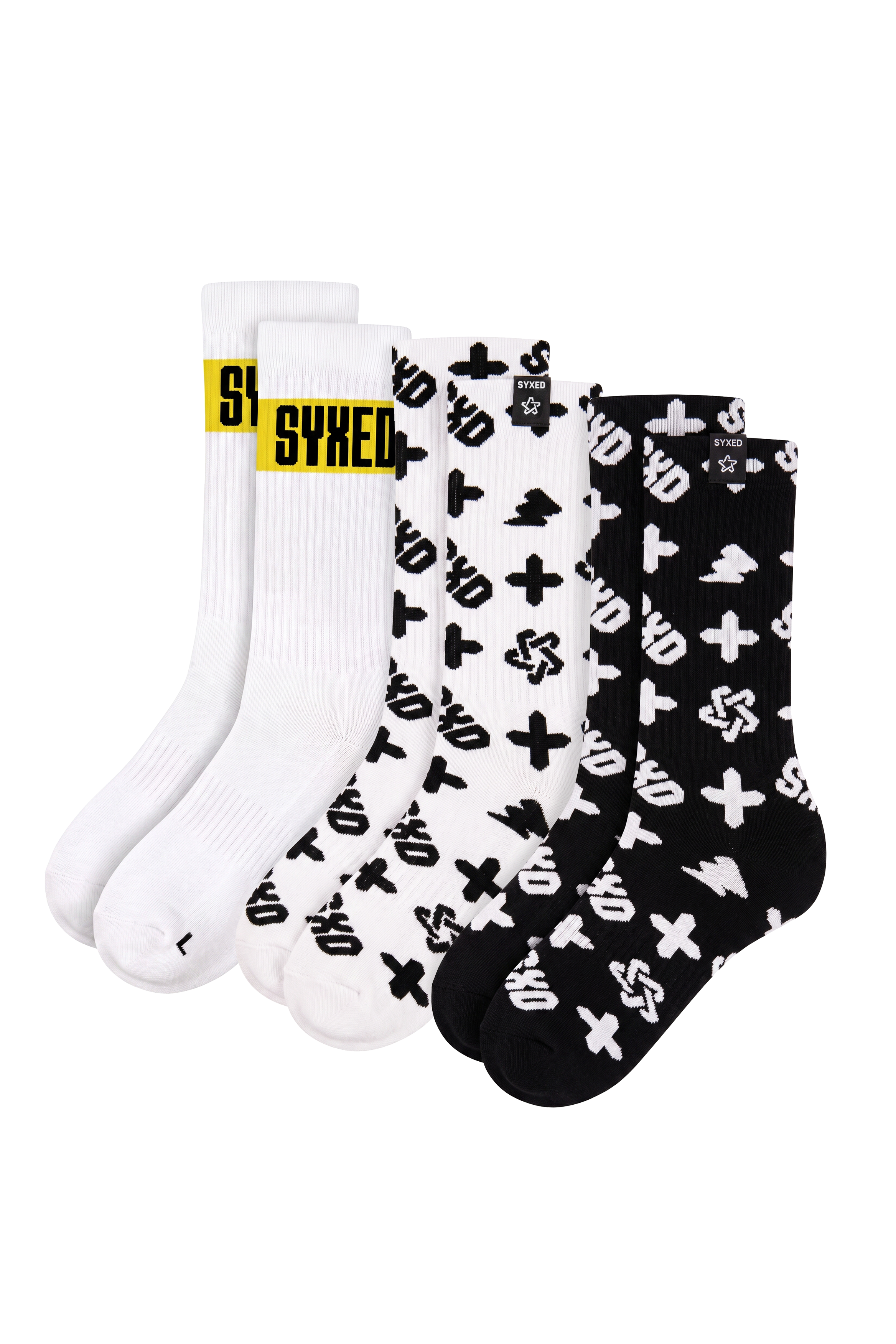 A 3-pack of crew socks from Syxed, featuring white and black colorways with graphic patterns. The front sock is white with a bold yellow 'SYXED' logo, the middle sock is white with black graphic symbols, and the back sock is black with white graphic symbols.