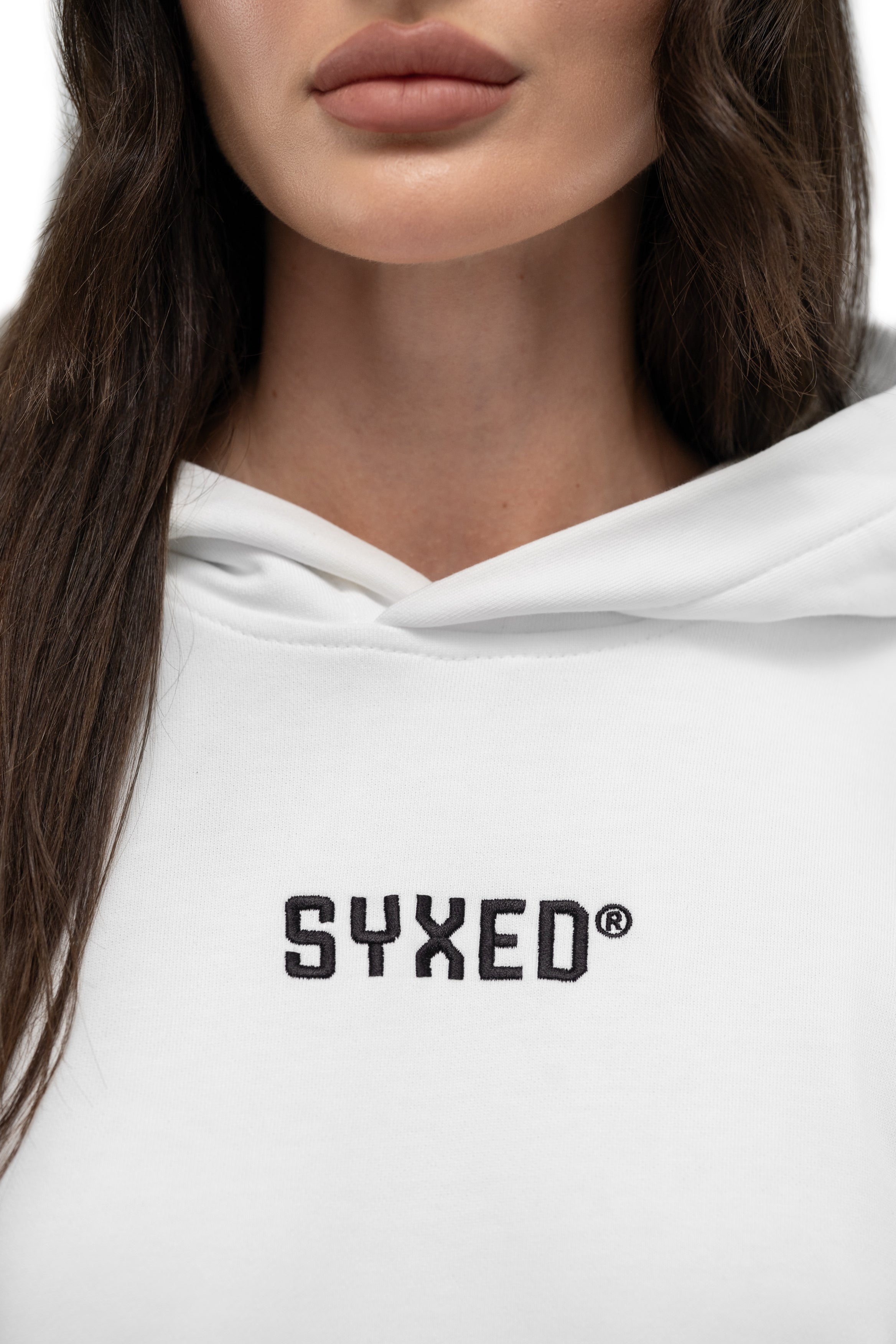 Close-up of a person wearing a white hoodie with the brand name 'SYXED' printed in black across the chest.